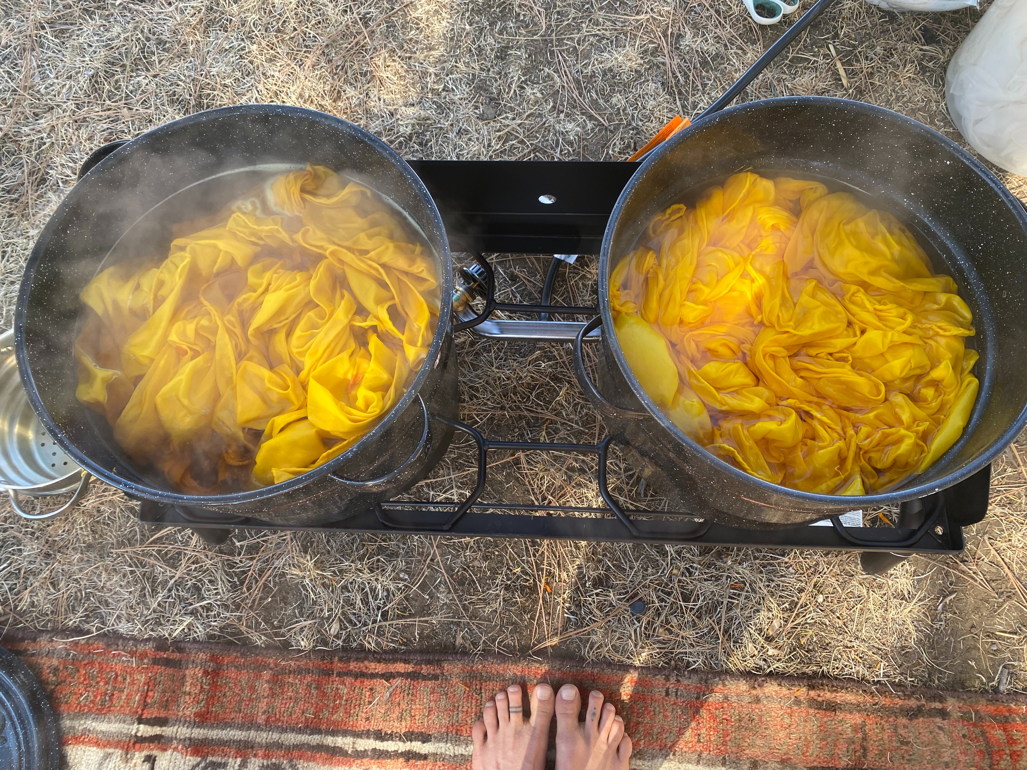 Silks brewing in a marigold natural dye in pots on the stove outside.